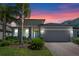 Charming single-story home with a two-car garage, landscaped yard, and brick-paved driveway during a vibrant sunset at 861 Grazie Loop, Davenport, FL 33837