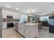 Open-concept kitchen with stainless steel appliances, a center island, pendant lighting, and a seamless view of the living room at 861 Grazie Loop, Davenport, FL 33837