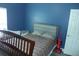 Bedroom with natural light has a cozy bed, crib and blue accent wall at 908 Hilly Bend Dr, Apopka, FL 32712
