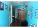 Hallway with aqua walls, dark hardwood floors, and an open doorway leading to another room at 908 Hilly Bend Dr, Apopka, FL 32712
