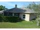 Back exterior view showcasing the enclosed patio and the well-maintained backyard with a hedge at 908 Hilly Bend Dr, Apopka, FL 32712