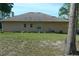 Rear exterior view of the house, showing neutral siding, small windows, and green lawn at 908 Hilly Bend Dr, Apopka, FL 32712