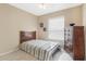 A bedroom featuring striped bedding, a ceiling fan, a wooden dresser, and natural light from a window at 10321 Pebblestone Ct, Leesburg, FL 34788