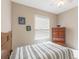 A bedroom featuring striped bedding, a ceiling fan, a wooden dresser, and a sunlit window at 10321 Pebblestone Ct, Leesburg, FL 34788