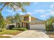 Lovely two-story home showcasing stone accents, a small balcony, and an attached two-car garage at 10321 Pebblestone Ct, Leesburg, FL 34788