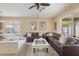Inviting living room with a large leather sectional, bright white armchair, and a sliding patio door at 10321 Pebblestone Ct, Leesburg, FL 34788