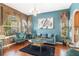 Living room showcasing hardwood floors, blue walls, modern furniture, and natural light from the window at 10321 Pebblestone Ct, Leesburg, FL 34788