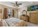 A main bedroom featuring neutral tones, a ceiling fan, and a dresser with ornate detailing at 10321 Pebblestone Ct, Leesburg, FL 34788