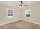 Bright bedroom featuring two windows, tan walls, neutral carpet and ceiling fan at 1179 Seminole St, Clermont, FL 34711
