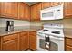 Kitchen featuring wood cabinets, granite countertops, white appliances and breakfast bar at 13427 Blue Heron Beach Dr # 1802, Orlando, FL 32821