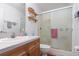Cozy bathroom with wood cabinets, vanity, toilet, and a shower with glass doors at 14325 Golden View Dr, Grand Island, FL 32735