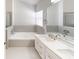 Modern bathroom with neutral tile accents, a soaking tub, a double sink vanity, and bright natural light at 193 Lansbrook Ct, Ocoee, FL 34761