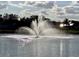 Picturesque water fountain in pond with reflective water and cloudy sky at 193 Lansbrook Ct, Ocoee, FL 34761