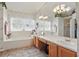 Bright bathroom featuring a large mirror, double sinks, soaking tub, and plenty of natural light at 20705 Nettleton St, Orlando, FL 32833