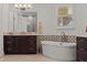 Bathroom boasts dual vanities, granite countertops, and a modern soaking tub with decorative tile backsplash at 225 Magnolia St, Windermere, FL 34786