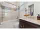 Bathroom featuring a dark wood vanity, marble countertops, and a shower-tub combination with a glass door at 225 Magnolia St, Windermere, FL 34786