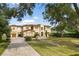 Stately two-story home with a circular driveway, manicured lawn, and elegant landscaping at 225 Magnolia St, Windermere, FL 34786