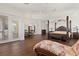 Expansive main bedroom featuring a four-poster bed, hardwood floors, and comfortable chaise lounge at 225 Magnolia St, Windermere, FL 34786