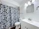 Well-lit bathroom features a white vanity, a toilet, and a shower with a decorative curtain at 2617 S Marshall Ave, Sanford, FL 32773