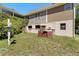 Image shows the back of a beige house with a green-brown lawn and some utility structures at 3149 Scrub Oak Trl, Oviedo, FL 32765
