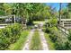 View of a gated gravel driveway lined by green shrubbery leading into a verdant tree-lined property at 3149 Scrub Oak Trl, Oviedo, FL 32765