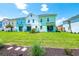 A well-kept lawn extends behind a row of colorful townhomes with outdoor seating and sliding glass doors at 3192 Caribbean Soul Dr, Kissimmee, FL 34747