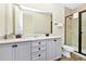 Bathroom with double sink vanity, neutral tiling, and glass door walk-in shower at 3192 Caribbean Soul Dr, Kissimmee, FL 34747