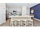 Bright kitchen with an eat-in bar, white cabinets, stainless steel appliances, and wood tile flooring at 3192 Caribbean Soul Dr, Kissimmee, FL 34747