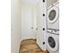 Bright laundry room features a stackable washer and dryer, white door, and wood-look tile flooring at 3192 Caribbean Soul Dr, Kissimmee, FL 34747