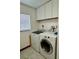 Functional laundry room with washer, dryer, overhead cabinet, and tiled flooring at 324 Bonita Rd, Debary, FL 32713
