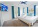 Bright bedroom with white linens, light-wood bed frame, blue accents, ceiling fan, and outdoor balcony access at 4720 Hemingway House St, Kissimmee, FL 34746