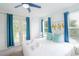 Bright bedroom with white linens, light-wood bed frame, blue accents, and view of the trees through windows at 4720 Hemingway House St, Kissimmee, FL 34746