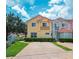 A townhome featuring a red tile roof, black iron balcony, yellow exterior, and a well-kept lawn at 4720 Hemingway House St, Kissimmee, FL 34746
