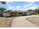 Charming single-story home with solar panels, a stone facade, two-car garage, and a curved driveway at 690 S Lakemont Ave, Winter Park, FL 32792