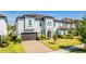 Beautiful two-story home with a well-manicured lawn, brick driveway, and gray stucco exterior at 8384 Ludington Cir, Orlando, FL 32836