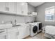 Well-equipped laundry room with washer, dryer, storage cabinets, countertop, and sink at 8384 Ludington Cir, Orlando, FL 32836