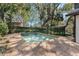 Backyard pool surrounded by brick patio, mature landscaping, and wrought iron fence at 9676 Wild Oak Dr, Windermere, FL 34786