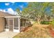 Backyard featuring a screened porch and a large tree providing shade at 1002 Kelsey Ave, Oviedo, FL 32765