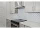 Close-up of the cooktop with stainless steel hood vent and white backsplash at 13532 Autumn Harvest Ave, Winter Garden, FL 34787