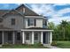 Exterior view of a two-story house with grey siding, black shutters and white pillars on the front porch at 13817 Luna Harvest Ave, Winter Garden, FL 34787