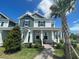 Charming two-story home featuring a welcoming front porch, manicured lawn, and a beautiful palm tree at 13817 Luna Harvest Ave, Winter Garden, FL 34787