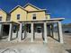 New two-story home under construction featuring yellow siding and a covered porch with gray support columns at 13817 Luna Harvest Ave, Winter Garden, FL 34787