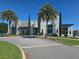 Exterior of community clubhouse, professionally landscaped with palm trees, lawn and paved entryway at 15149 Canoe Pl, Winter Garden, FL 34787