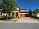 Charming two-story home featuring a red tile roof, arched entryway, a three-car garage, and lush landscaping at 15149 Canoe Pl, Winter Garden, FL 34787
