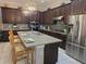 Spacious kitchen featuring dark wood cabinets, granite countertops, stainless steel appliances, and a large center island at 15149 Canoe Pl, Winter Garden, FL 34787