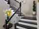 Elegant staircase with black and white accents, wrought iron railings, and decorative floral arrangements at 15149 Canoe Pl, Winter Garden, FL 34787