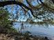 Scenic waterfront view showcasing tranquil blue water, remnants of a pier, and lush greenery under a clear blue sky at 1933 Bayview Dr, New Smyrna Beach, FL 32168