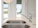 Close-up of a stainless steel kitchen sink and chrome faucet in a kitchen with natural light and quartz countertops at 2290 Sw Raven Ridge Rd, Clermont, FL 34715