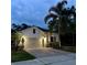 Well-lit home exterior at dusk featuring a two-car garage and tropical landscaping at 2301 Avellino Ave, St Cloud, FL 34771
