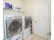 Bright laundry room featuring stainless steel washer and dryer, white cabinets and storage shelves at 2942 Wordsmith Rd, Kissimmee, FL 34746